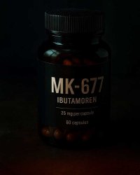 Чёрная банка с капсулами MK-677 (Ибутаморен) в дозировке 25 мг на фоне глубокой тени, что служит иллюстрацией к статье, детально объясняющей, нужна ли ПКТ после курса ибутаморена и как этот миметик грелина влияет на гормональные оси организма.